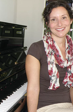 Erin Parkes sitting in front of a piano smiling