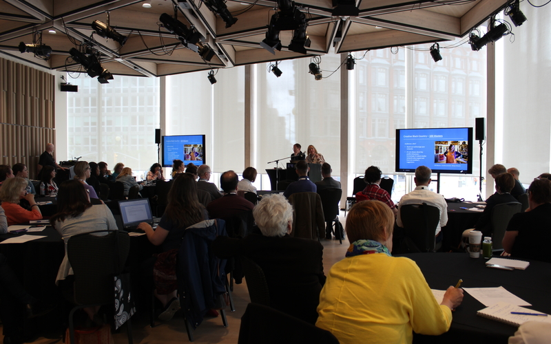 Man and lady speaking to audience with a PowerPoint presentation 