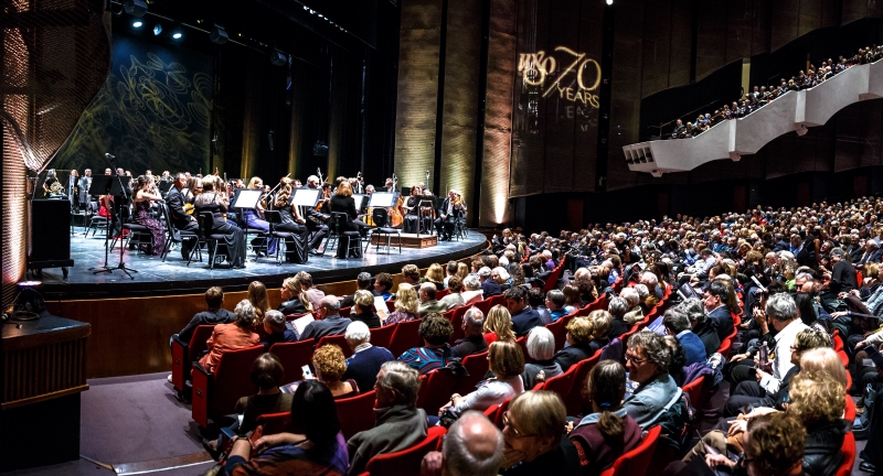 Orchestra on stage with a full audience